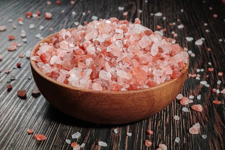 Wooden bowl filled with coarse Himalayan pink salt crystals