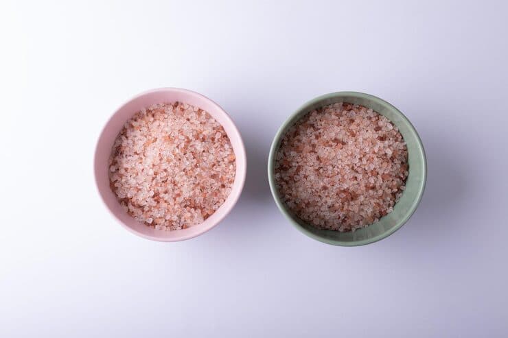 Pink rock salt crystals in bowls on a white background